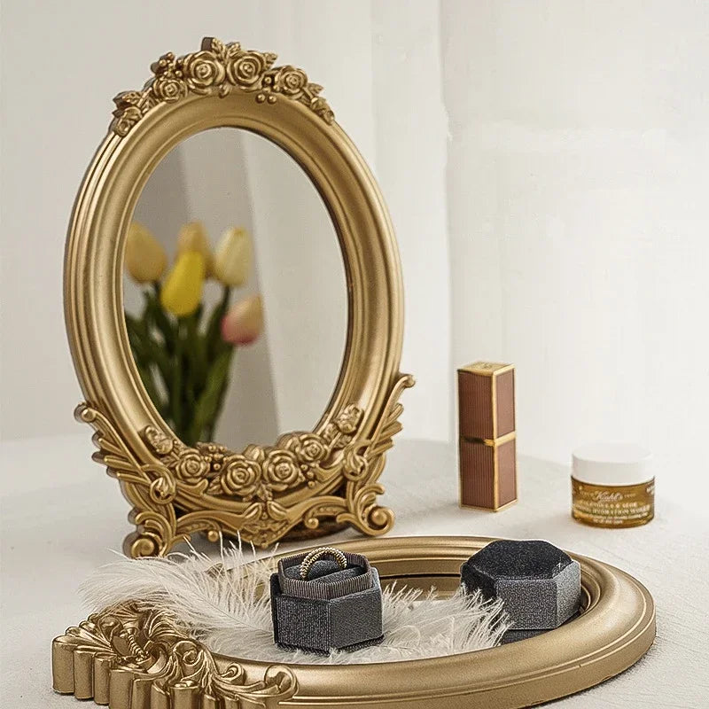 Miroir de table ovale doré à cadre de roses, avec une bague et un rouge à lèvres devant