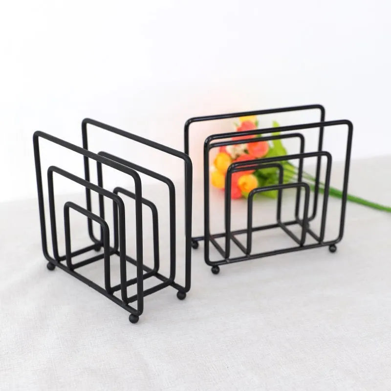 Deux supports à serviettes noirs à compartiments rectangulaires en fil métallique, devant un bouquet de fleurs