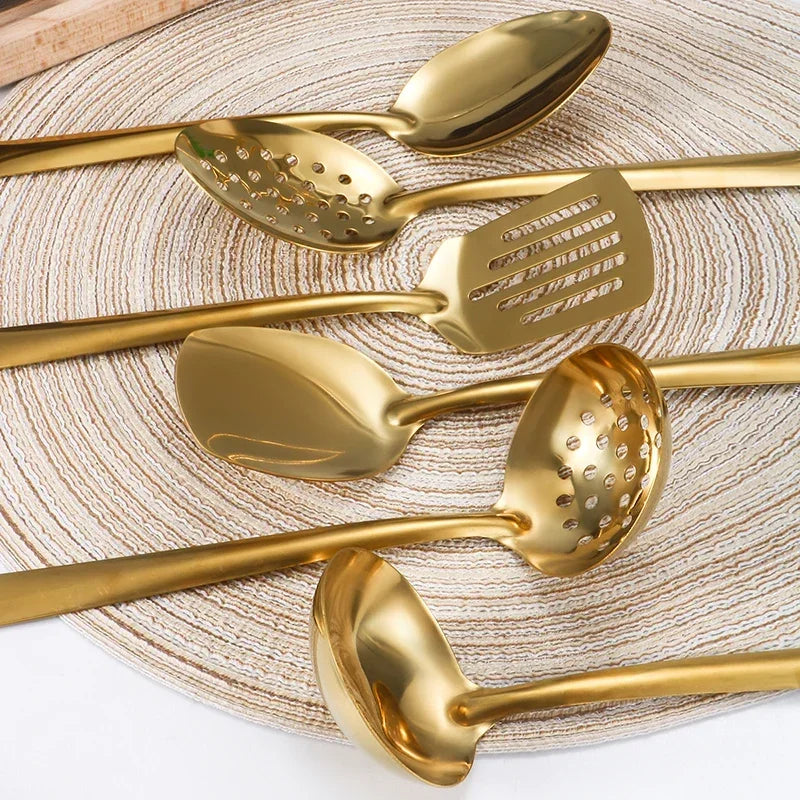 Détail de cuillères, de louche perforée et de spatule dorées, aux manches fins