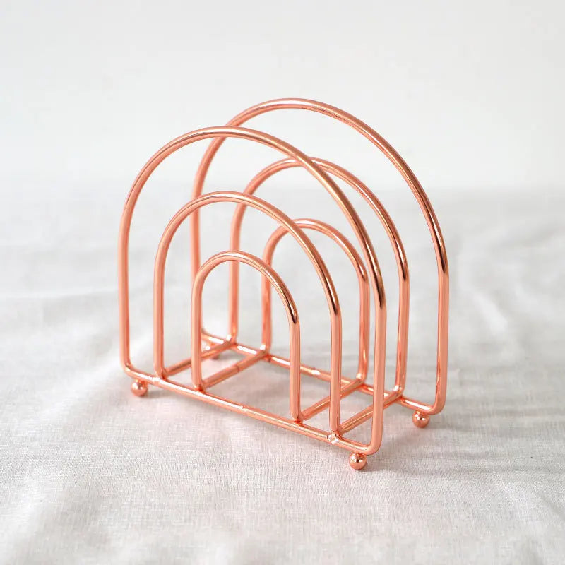 Porte-serviettes à arches concentriques rose cuivré, variante Rose Arche, posé sur un tissu blanc