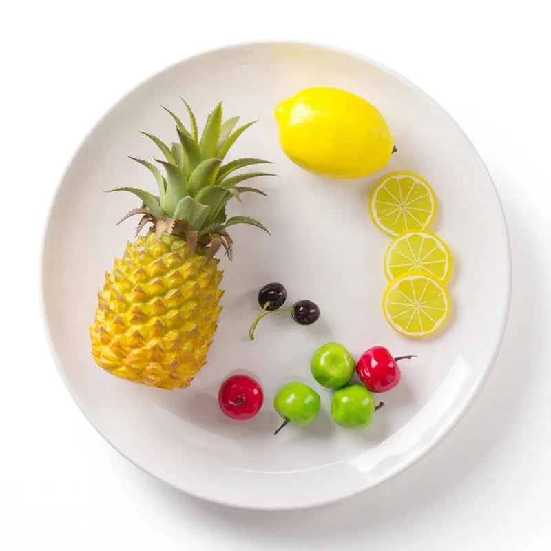 Assiette ronde blanche garnie d'ananas, de citron et de fruits