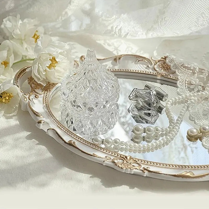 Plateau miroir ovale blanc et doré avec un bocal en cristal et des colliers de perles