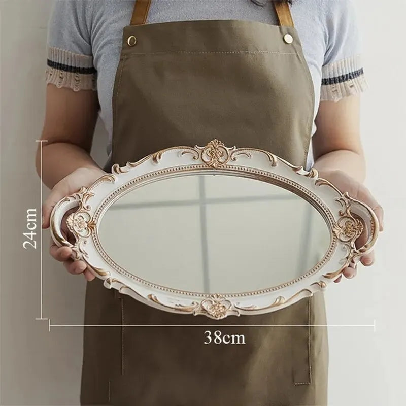 Plateau miroir ovale blanc et doré de 38 x 24 cm tenu à deux mains