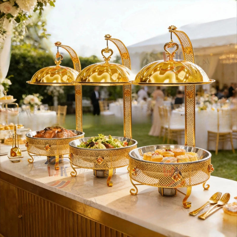 Trois chauffe-plats dorés à couvercle suspendu sur un buffet de mariage en extérieur