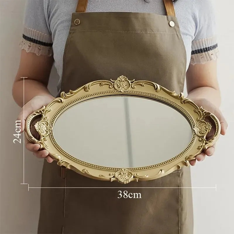 Plateau miroir ovale doré de 38 cm de large tenu à deux mains, avec ses dimensions