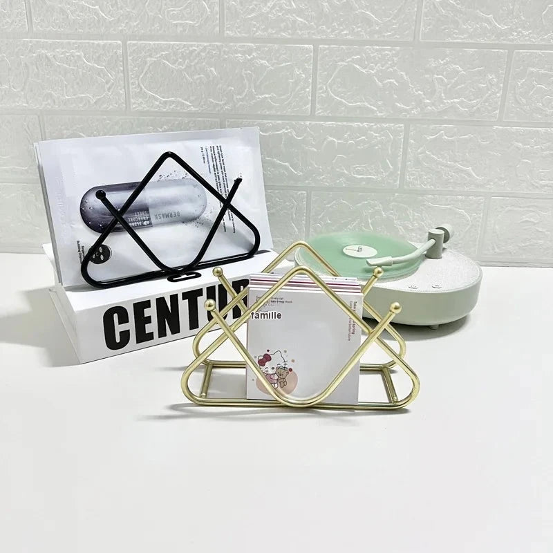 Porte-serviettes triangulaires noir et doré posés sur un meuble blanc, avec sachets et cartes dans les fentes