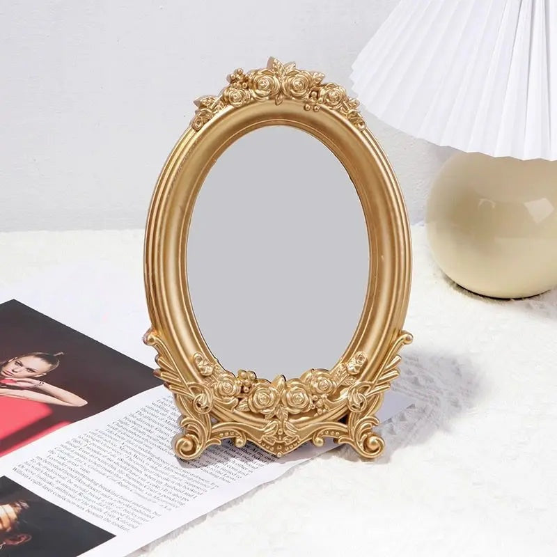 Miroir de table ovale doré à cadre de roses posé sur un magazine