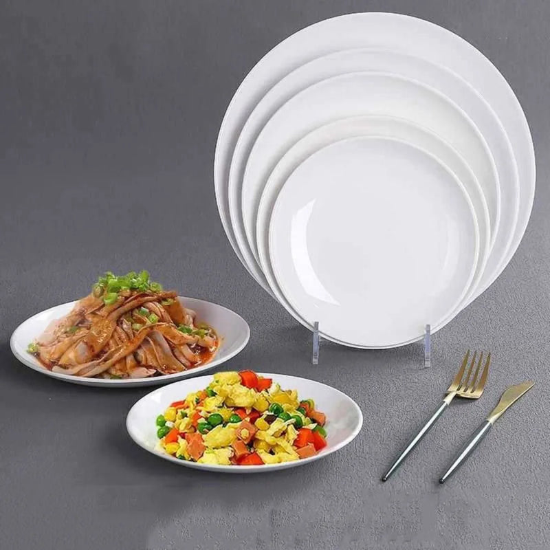 Pile d'assiettes blanches rondes avec deux assiettes garnies de plats cuisinés