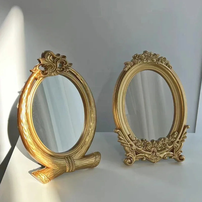 Deux miroirs de table ovales dorés à cadre sculpté, posés sur un fond gris-bleu
